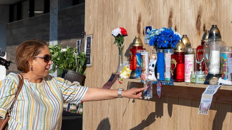 Josephine Sanchez, of Deer Park, places flowers at a makeshift memorial...
