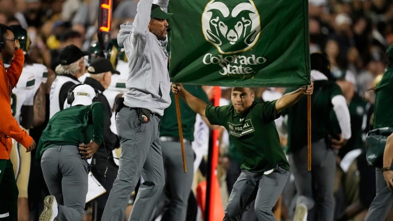 Colorado State head coach Jay Norvell, front left, jumps while...