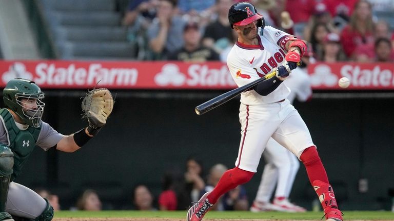 Los Angeles Angels' Zach Neto, right, swings at a pitch...