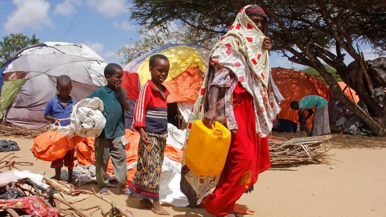 A woman walks with her children, who fled amid drought,...