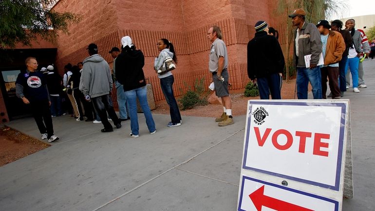 Voters stand in line to cast their ballots at the...