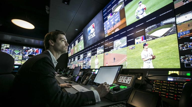 Workers demonstrate Major League Baseball's instant replay center, located in...