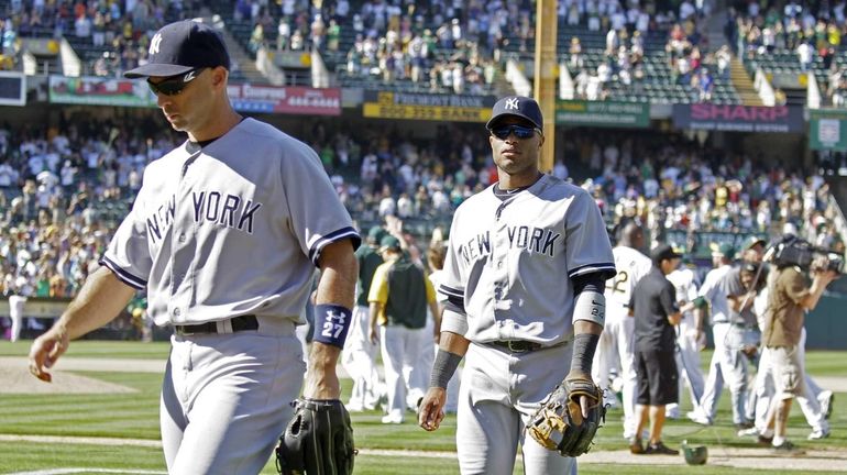 Raul Ibanez, left, and Robinson Cano walk off the field...