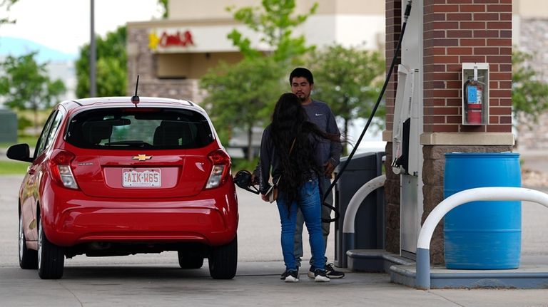 Motorists fill up the tank of a car at a...