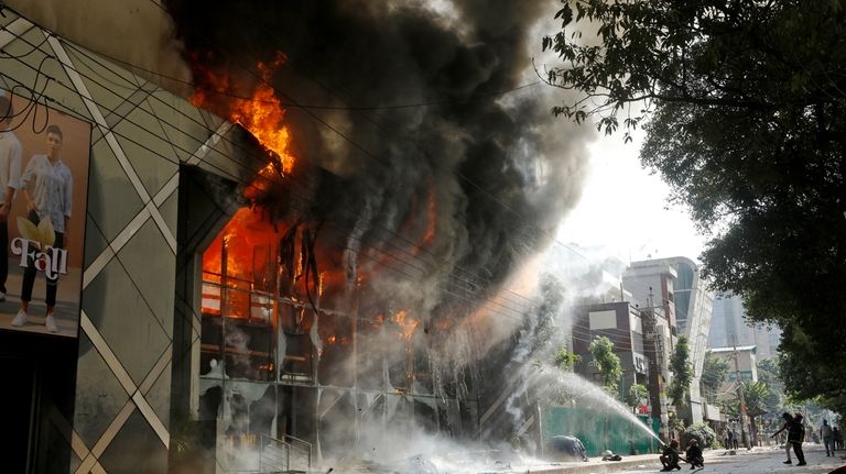 Firefighters douse a fire engulfing a shopping center which was...