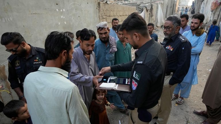 A Police officer conducts biometric identifying of a resident during...