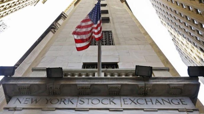 The American flag flies above the Wall Street entrance to...