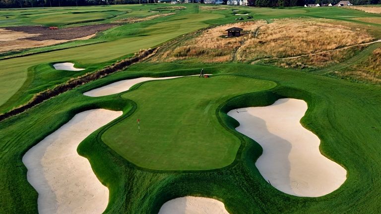 The thirteenth green gets mowed at Oakmont Country Club, in...