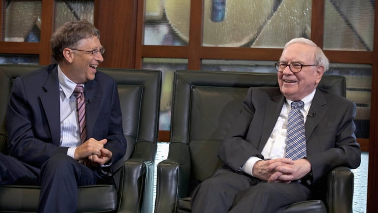 Warren Buffett, chairman and CEO of Berkshire Hathaway, right, looks...