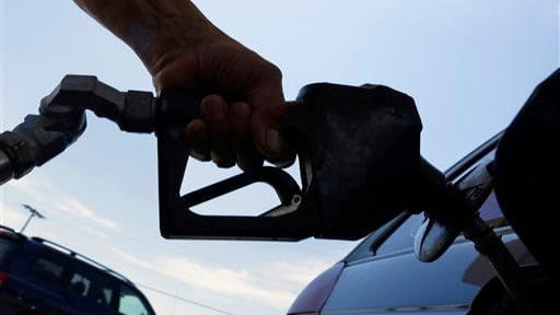 A motorist puts fuel in his car's gas tank at...
