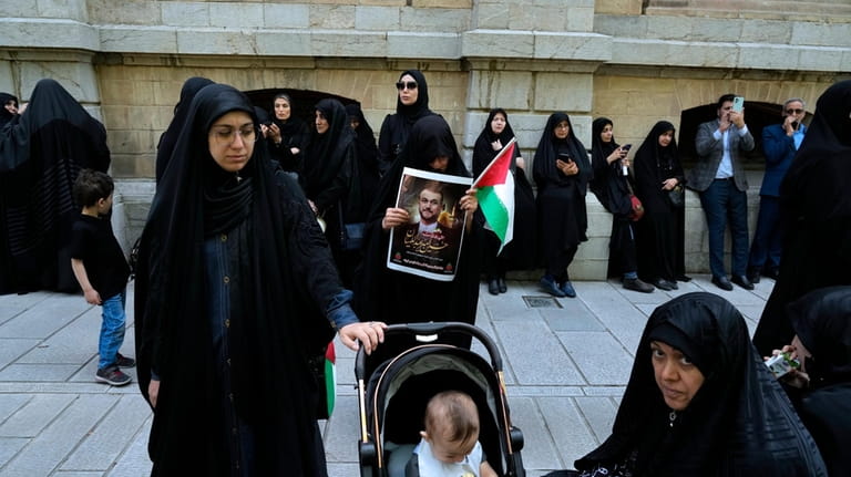 A woman holds a poster of the late Iranian Foreign...