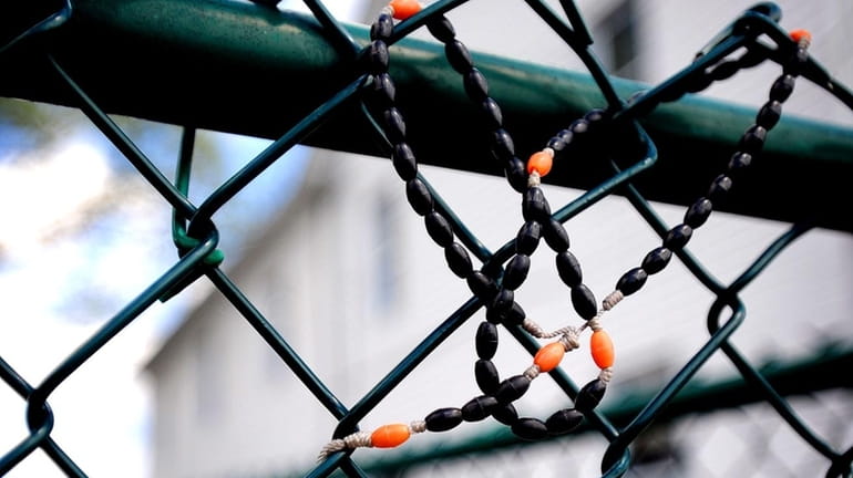 Rosary beads are wrapped into a chain link fence, Monday,...