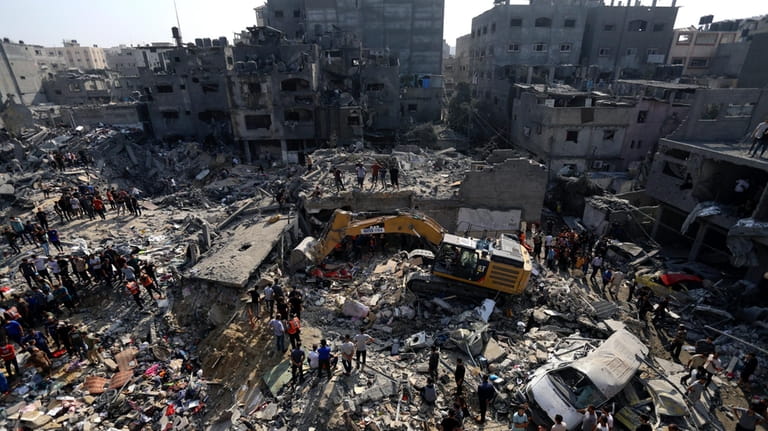 Palestinians look for survivors under the rubble of destroyed buildings...
