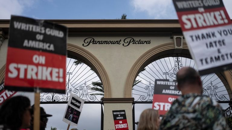 Demonstrators walk with signs during a rally outside the Paramount...