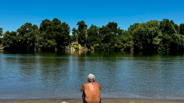 A man cools off by the river in Sacramento, Calif.,...