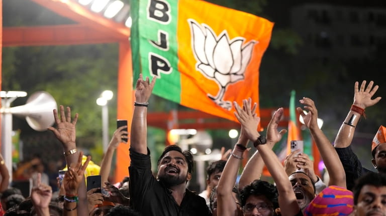 Bharatiya Janata Party (BJP) supporters shout slogans as they listen...