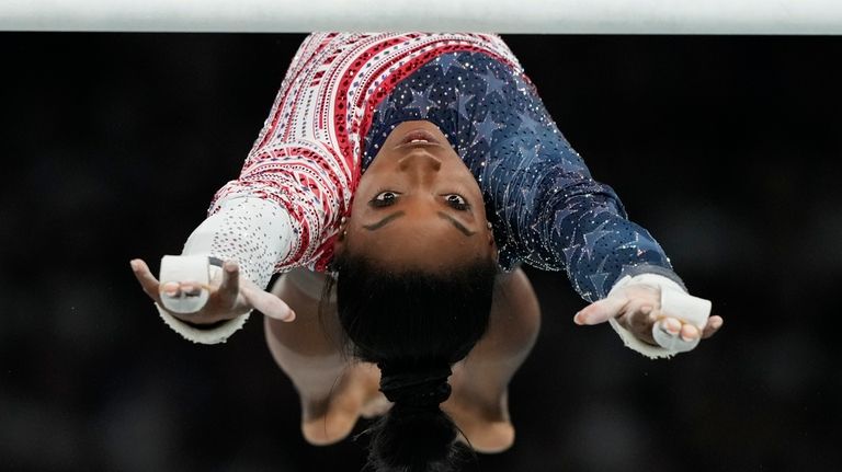 Simone Biles, of the United States, performs on the uneven...