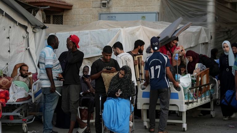 Patients and families move outside the Al-Aqsa Martyrs Hospital in...