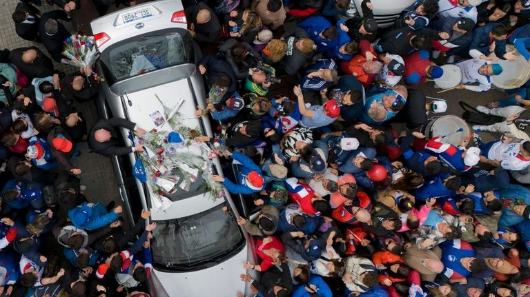 People surround the hearse carrying the remains of soccer player...