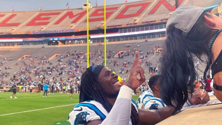 Carolina Panthers outside linebacker Luigi Vilain, left, gives autographs at...