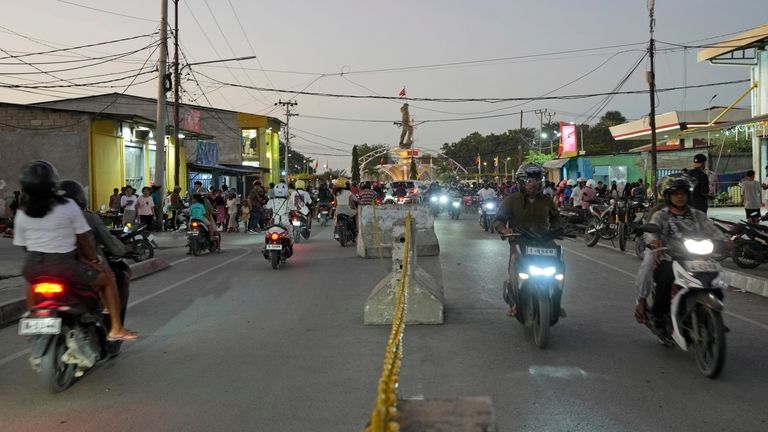 Motorcyclists move along a street where vendors have been removed...