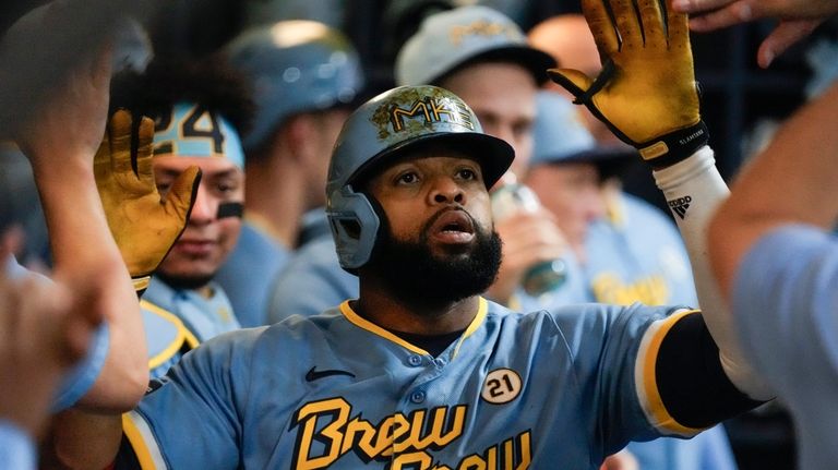 Milwaukee Brewers' Carlos Santana is congratulated after hitting a home...