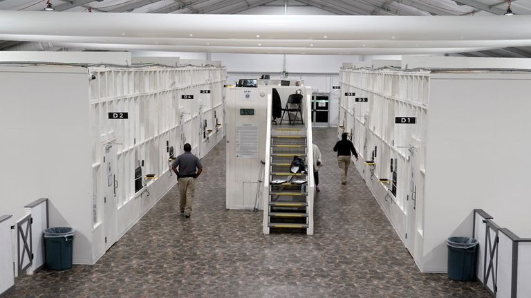 Agents walk among rooms at a Border Patrol holding facility...