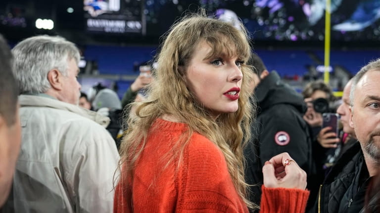 Taylor Swift speaks with people on the field after an...