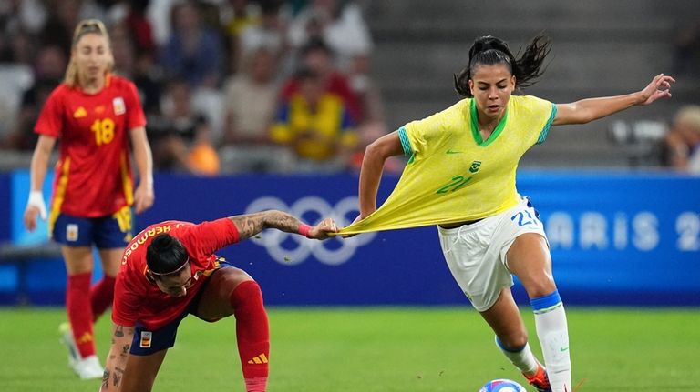 Spain's Jennifer Hermoso, left, pulls on the jersey of Brazil's...