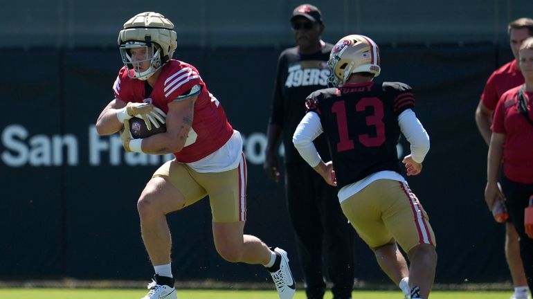 San Francisco 49ers running back Christian McCaffrey, left, runs after...