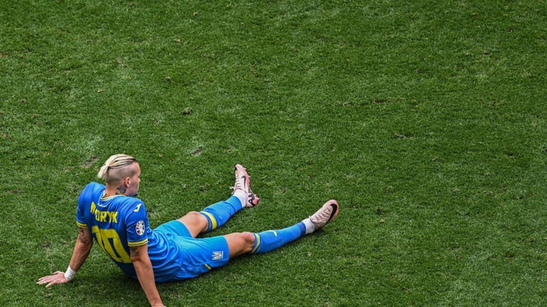 Ukraine's Mychajlo Mudryk sits on the pitch after a Group...