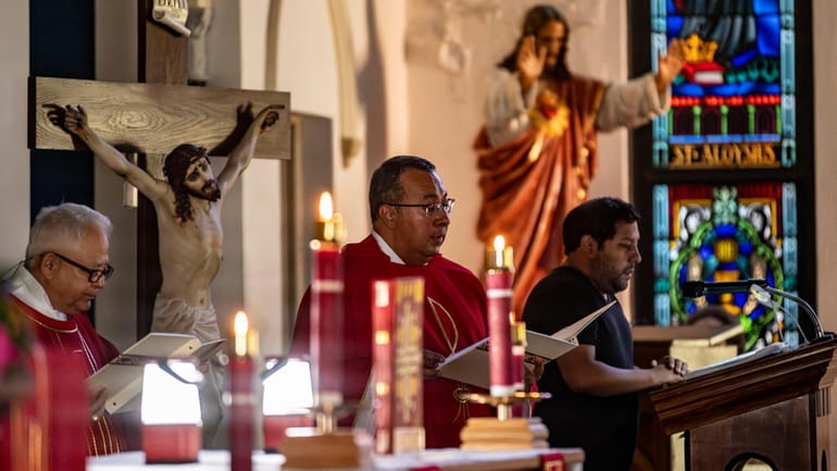 Father Elias Lopez reads by candle light during Sunday morning...