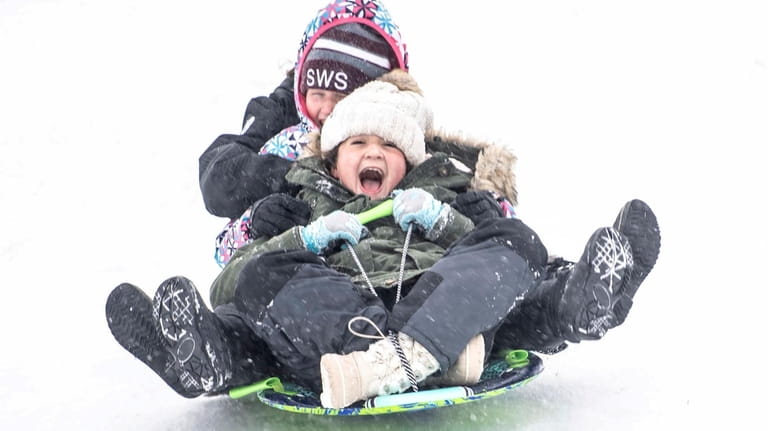 Two 10-year-olds sled down a hill at Cedar Park in Wantagh...
