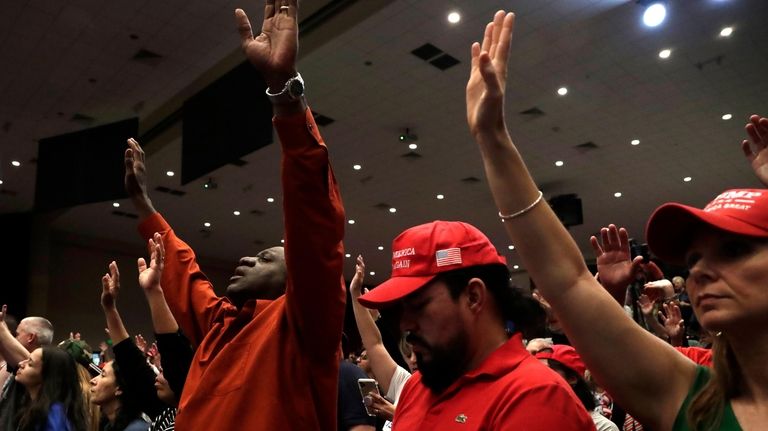 People raise their arms in prayer during a rally for...