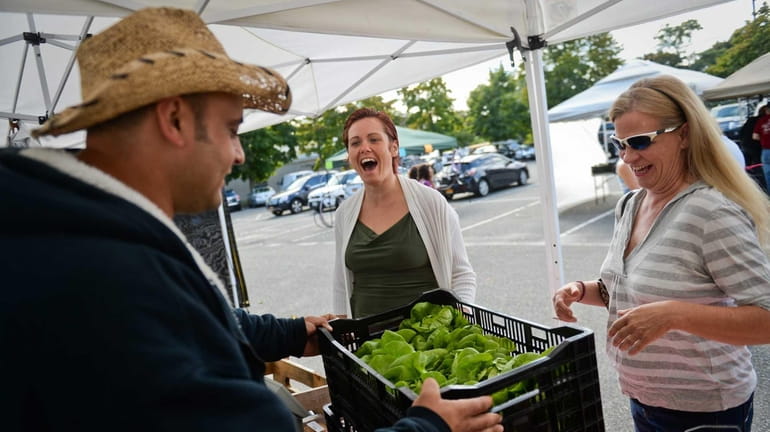 Shane Mott, center, and Susan Valiando, right, buy boston lettuce...