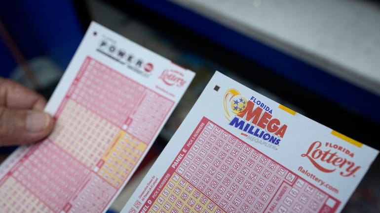 A lottery player holds forms to pick numbers for the...