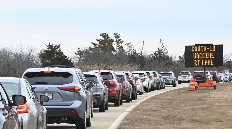 Vehicles line up at a COVID-19 vaccine site at Jones...