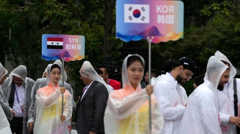 Volunteers hold country signs during team welcoming ceremony at the...