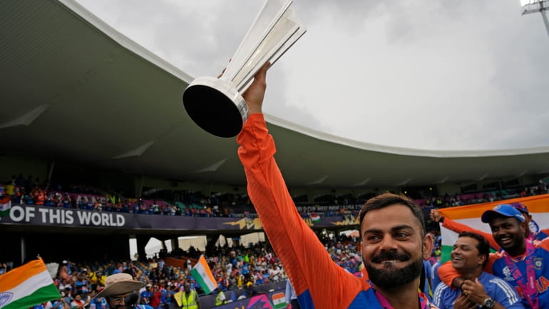 India's Virat Kohli carries the winners' trophy as he celebrates...