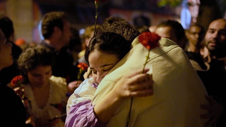 A couple hold red carnations while embracing each other after...