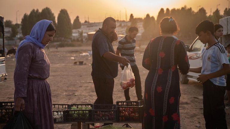 Residents buy vegetables at a market inside the Sharya displacement...