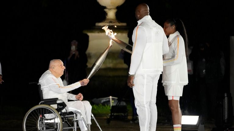 Charles Coste passes the flame to Teddy Riner and Marie-Jose...