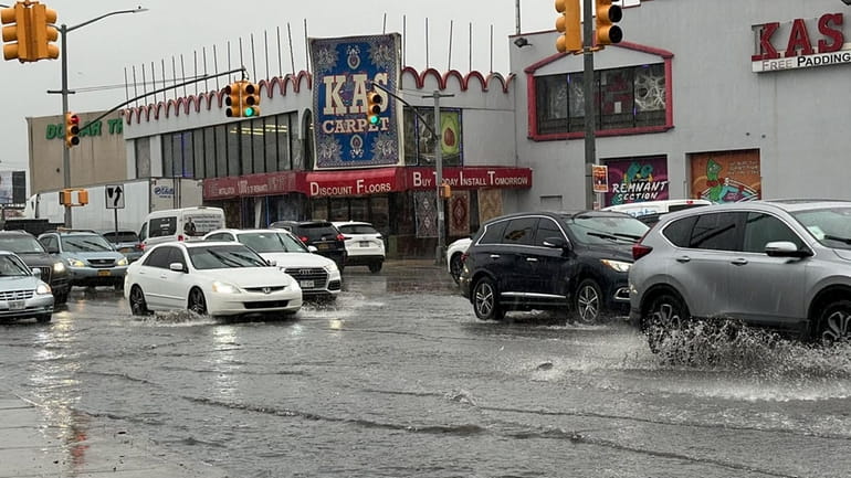 Cars splash through flooding on Rockaway Boulevard in Queens on Thursday morning.
