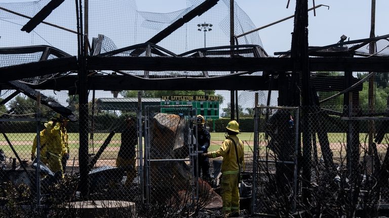 Firefighters remove debris at Jay Littleton Ball Park, a historic...