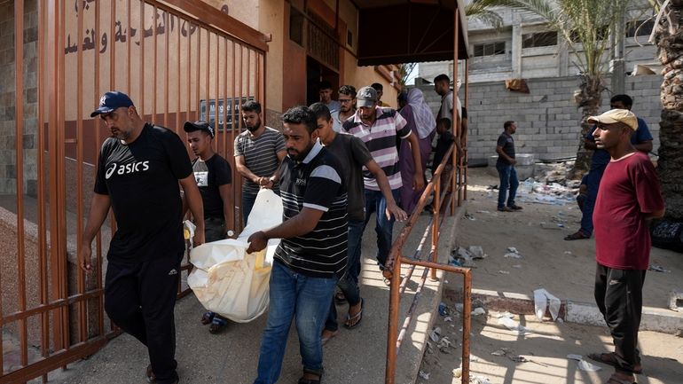 Mourners carry the covered bodies of Palestinians who were killed...