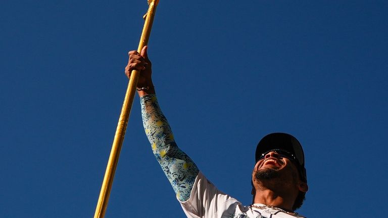 Seattle Mariners center fielder Julio Rodríguez holds up a trident...