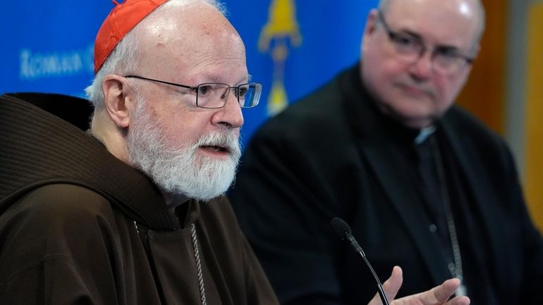 Cardinal Sean O'Malley, left, responds to a question from a...