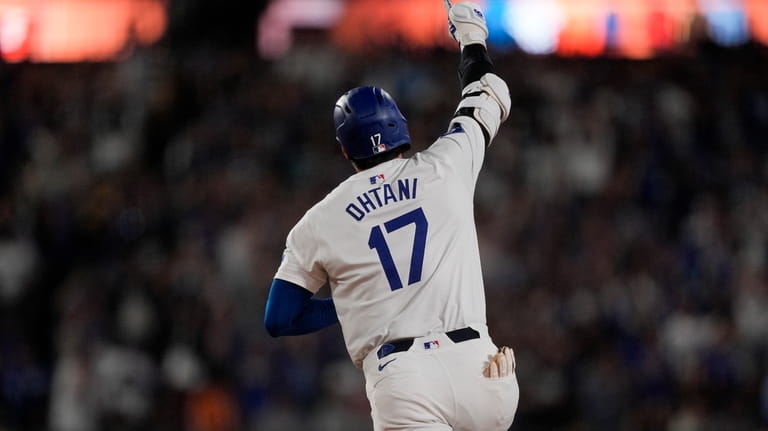 Los Angeles Dodgers designated hitter Shohei Ohtani celebrates while running...