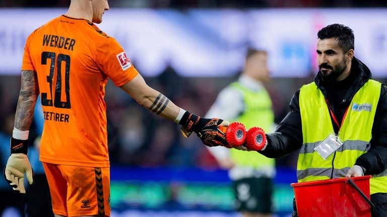 Bremen goalkeeper Michael Zetterer hands a steward a remote-controlled car...