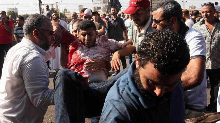 Egyptian demonstrators carry a fellow protester wounded after Muslim Brotherhood...